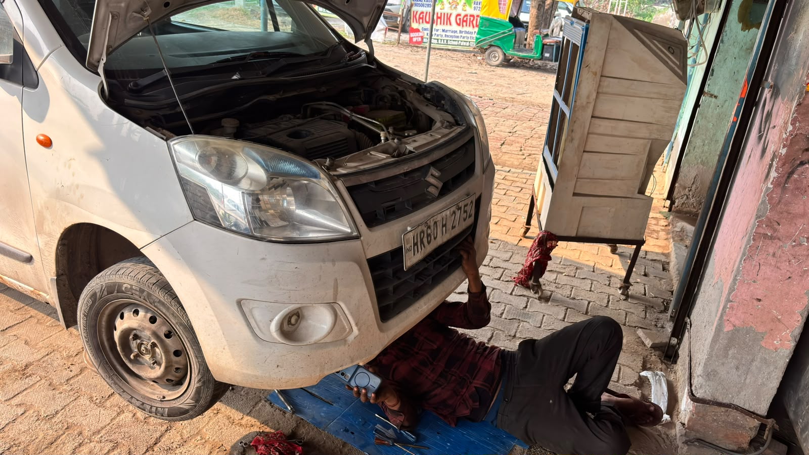 Mechanic of Mistri Car Mechanic working underneath a car with the bonnet open